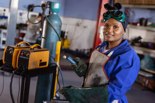Portrait of confident smiling mid adult african american female welder working in workshop