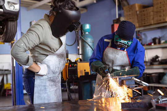 Mid adult multiracial female welders wearing protective workwear while working in workshop