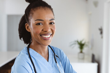 Portrait of smiling african american young female doctor with stethoscope around neck at home