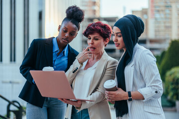 Businesswomen in street with laptop