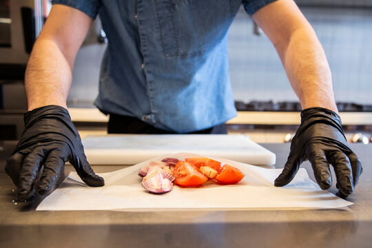 Anonymous chef With Sliced Onion And Tomato On Baking Paper