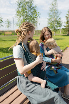 Mothers With Their Babies Sitting On Bench At Park