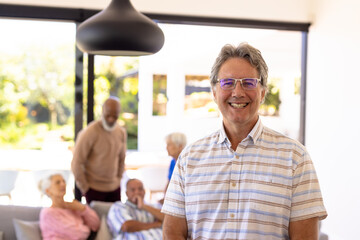 Portrait of smiling caucasian senior man standing with multiracial friends in background
