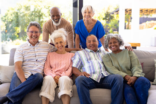 Portrait Of Happy Multiracial Male And Female Senior Friends Relaxing In Living Room At Nursing Home