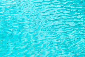 Fototapeta na wymiar Ripple Water in swimming pool with blue tile floor background