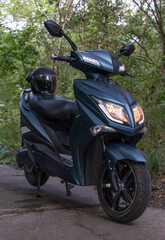 electric motorcycle with a helmet on the seat, stands on a forest road © OLEKSANDR