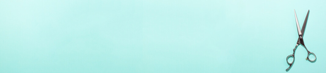 Banner flat lay of professional hair cutting shears on the right side on blue cyan background....