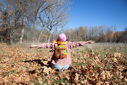 Mujer alegre lanzando hojas de otoño en el aire