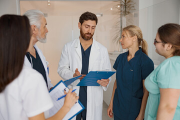 Obraz premium Group of doctor colleagues discussing patient diagnosis stand in clinic hall