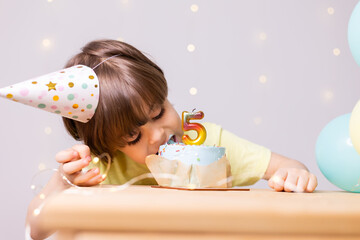 cute little birthday boy eating cake in hat, balloons, happy birthday