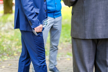 Empty glass champagne flute in male hand. Selective focus. A man in a blue suit holds an empty wine glass.