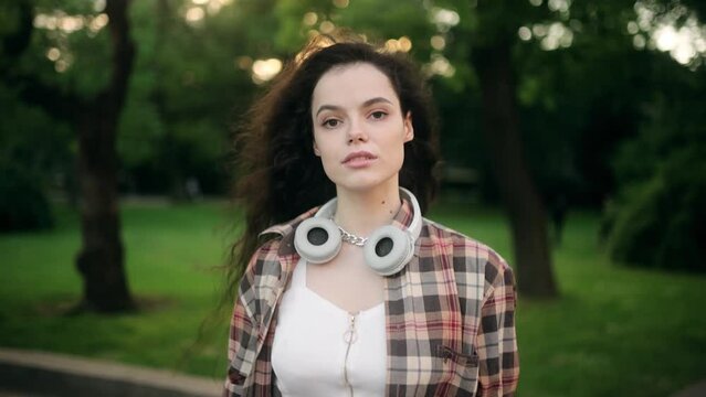 Portrait of a beautiful young woman in casual clothes on a walk in the park, looking at the camera
