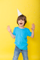 Handsome Little birthday boy in blue shirt and hat with balloons, yellow background, happy birthday