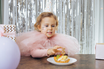 We celebrate five years. Charming girl with wavy red hair in party hat and pink festive outfit...