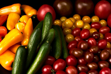 Set of delicious tomatoes, cucumbers and peppers on a black background
