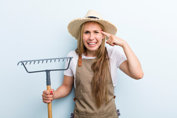 young adult blonde woman. farmer with a rake