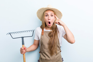young adult blonde woman. farmer with a rake