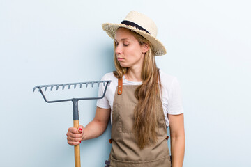 young adult blonde woman. farmer with a rake