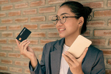 The Asian businesswoman's hand is holding a credit card and using a smartphone for online shopping and internet payment