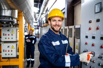 Portrait of an industrial electric engineer standing by power supply inside oil refinery.