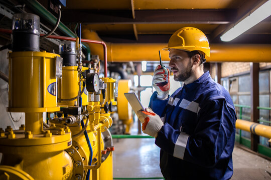 Professional industrial worker checking pressure of natural gas pipeline inside power plant or refinery.