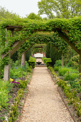 Fototapeta premium Looking down through pergola in the garden towards a water feature and seat 