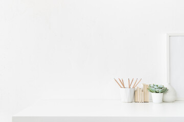 Creative desk with desk objects, office supplies, books and plant on a bright background.