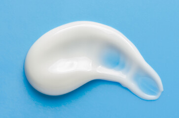 A sample of white moisturizer on a blue background. Cosmetic product for the skin.