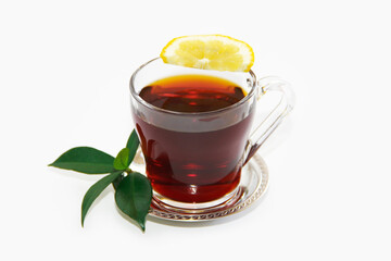 black tea in a transparent mug with a slice of lemon and green leaves