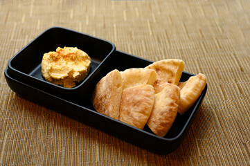 Homemade Bread and peanut butter are placed in black plates and put on a bamboo mat.