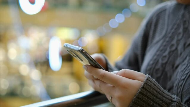 Shopping center. Moll. Finger of woman touching scroll page app on mobile phone. Browsing movie video in the internet library to watch film online.