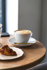 Cup of coffee and croissant on the table in cafe. Morning cafe, breakfast photo