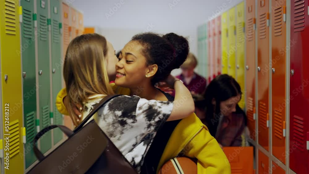 Wall mural young high school students meeting and greeting near locker in campus hallway talking and high fivin