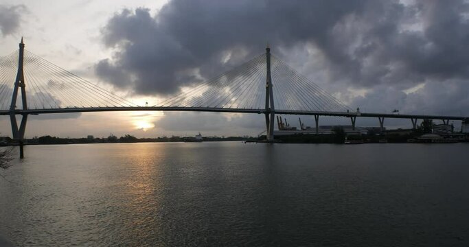 Bangkok boat and Chao Phraya River cruise under cloudy sun with bridge in the background, Thailand - timelapse photo