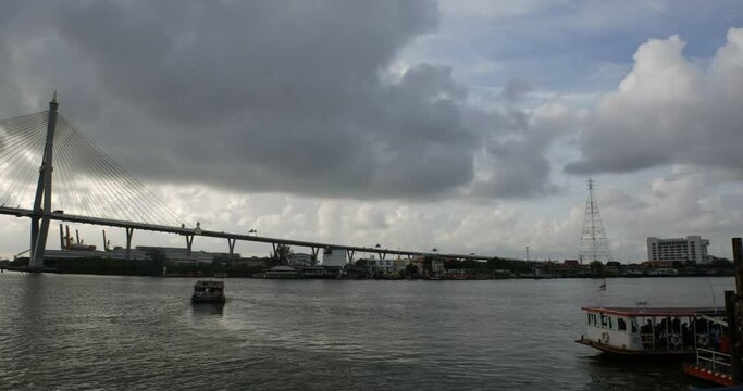 Bangkok boat and Chao Phraya River cruise under cloudy sun with bridge in the background, Thailand - timelapse photo