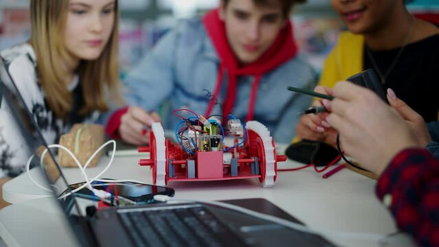 Group of high school students building and programming electric toys and robots at robotics classroom