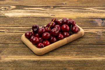 ripe red cherries in a wooden bowl on a wooden background