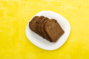 sliced rye bread in pieces in a white plate on a wooden background