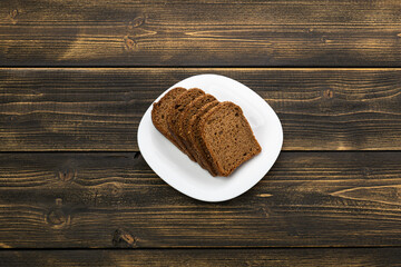 sliced rye bread in pieces in a white plate on a wooden background