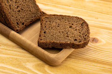 sliced rye bread in pieces in a wooden bowl on a wooden background