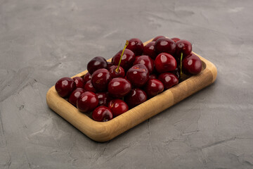 ripe red cherries in a wooden bowl on a stone background