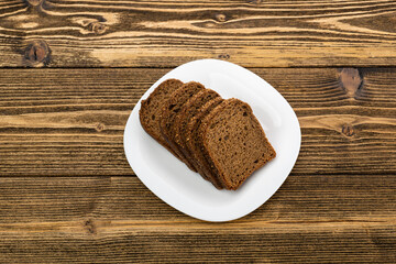 sliced rye bread in pieces in a white plate on a wooden background