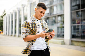 Portrait of modern young man with smartphone on a street. Hipster guy with mobile in his hand...