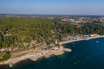 Aerial view of the coastline of Rovinj with forest and buildings on the road on the shore