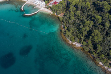 Fototapeta na wymiar Aerial view of beach and resorts on the coast of Rovinj with green blue clear water on the Adriatic sea