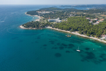 Obraz premium Aerial view of beach and resorts on the coast of Rovinj with green blue clear water on the Adriatic sea