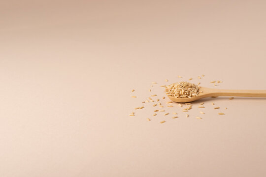 Wooden spoon with brown rice in a minimalist style. Front view