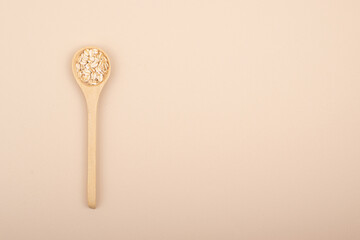 A minimalistic wooden spoon with natural oats. Top view