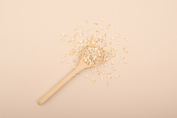A minimalistic wooden spoon with natural oats. Top view