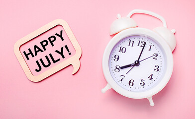 On a delicate pink background, a white alarm clock and a wooden frame with the text HAPPY JULY